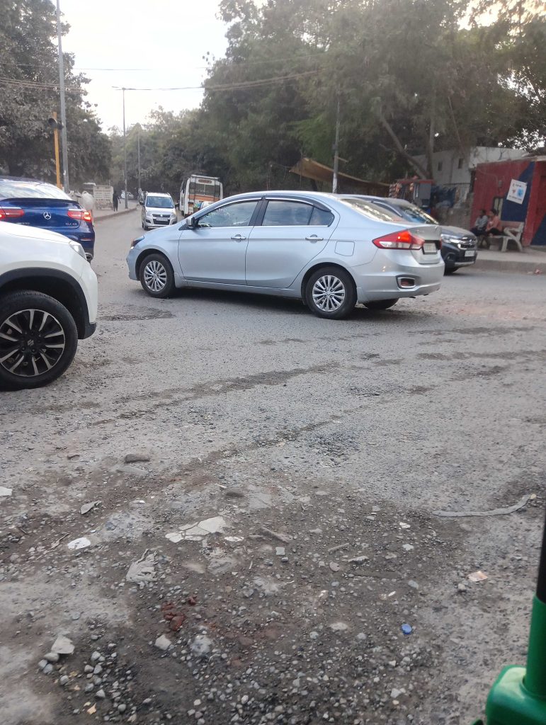 Cars passing over a potholed road in Delhi